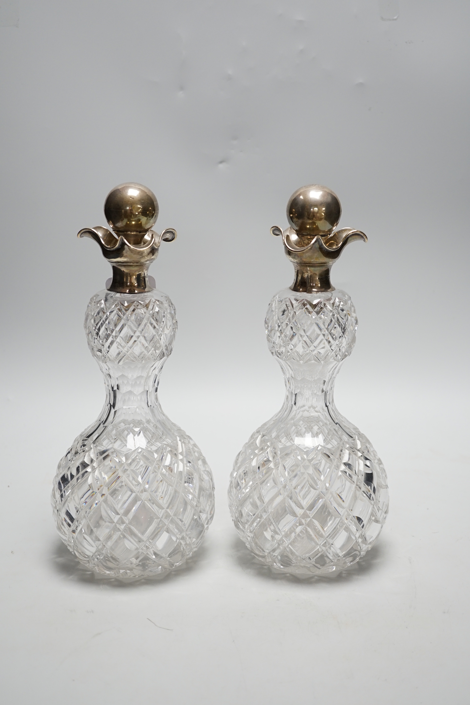 A pair of late Victorian silver mounted cut glass waisted tri-lipped decanters, with stoppers, John Grinsell & Sons, London, 1900, 28.5cm.